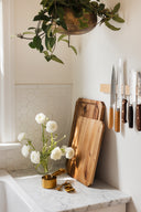 Kitchen corner with wooden cutting boards, knives, and white flowers on a marble countertop.