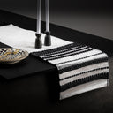 Black and white striped table runner on a dark surface with cutlery and plates.