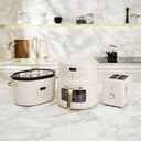 White kitchen appliances including a slow cooker, coffee maker, and toaster on a marble countertop.