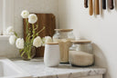 Decorative jars and a vase with flowers on a kitchen counter.
